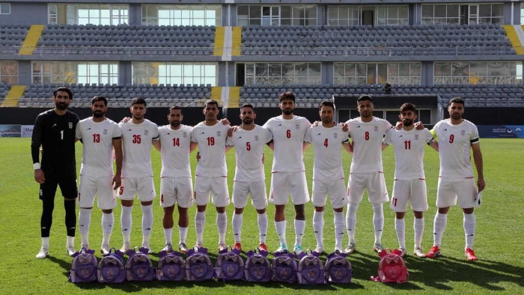 Iran’s soccer players hold schoolbags wearing black armbands in solidarity with slain girls